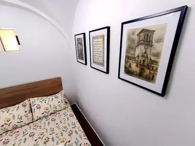 a bedroom with three pictures on the wall and a bed at Casita ENTREARCOS in Arcos de la Frontera