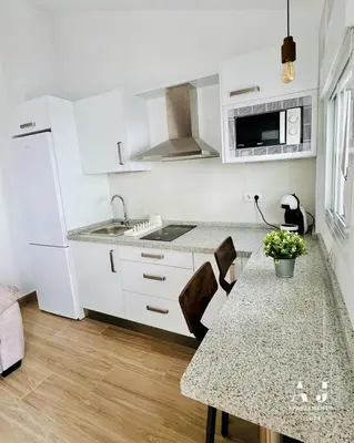a kitchen with white cabinets and a table with flowers on it at Loft Alegría de Jerez in Jerez de la Frontera