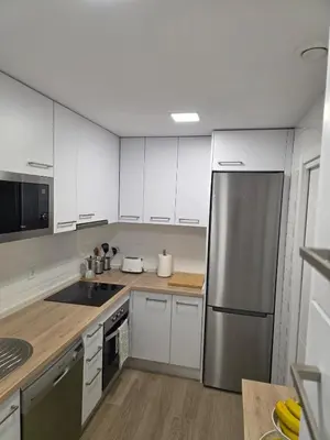 a kitchen with white cabinets and a stainless steel refrigerator at GINVA - Costa Ballena & Jardines de Majadales in Chipiona