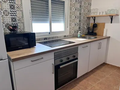a kitchen with a microwave and a stove and a sink at Apartamento Molino de Algarrobo in Arcos de la Frontera