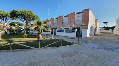 a building with a palm tree in front of it at Costa Playasol in Novo Sancti Petri