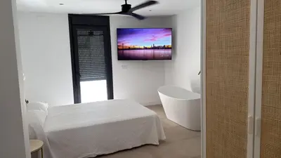 a white room with a bed and a tv on the wall at Casa Isabel in Chipiona
