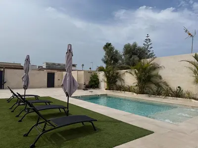 a group of chairs and umbrellas next to a swimming pool at Casa Isabel in Chipiona