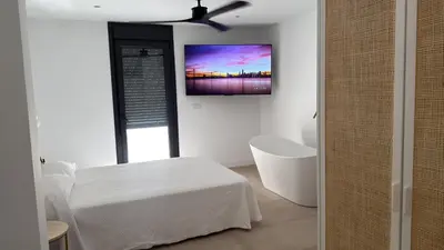a white room with a bed and a tv on the wall at Casa Isabel in Chipiona