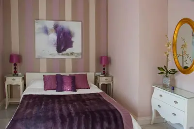 a bedroom with a bed with purple pillows and a mirror at Villa de Lujo con Jardines y Piscina in El Puerto de Santa María