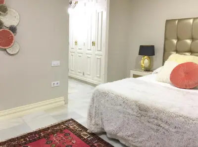 a bedroom with a bed with a red pillow on it at Villa de Lujo con Jardines y Piscina in El Puerto de Santa María