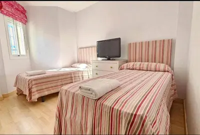 a room with two beds and a tv on the wall at Atardeceres en Bajoguía in Sanlúcar de Barrameda