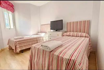 a room with two beds and a tv on the wall at Atardeceres en Bajoguía in Sanlúcar de Barrameda