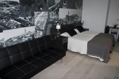 a black and white bedroom with a bed and a couch at Hotel Barrio Nuevo in Lebrija