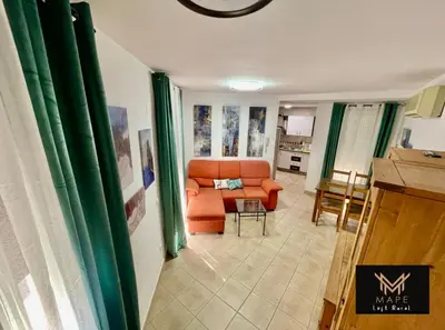 a living room with an orange couch and a kitchen at Mape Loft Rural El MIMBRAL in Algar
