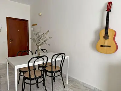 a white table with chairs and a guitar on the wall at El Compás de Jerez - Ole Solutions in Jerez de la Frontera
