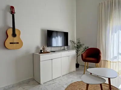 a living room with a flat screen tv and a guitar at El Compás de Jerez - Ole Solutions in Jerez de la Frontera