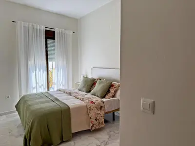 a white bedroom with a bed and a window at El Compás de Jerez - Ole Solutions in Jerez de la Frontera