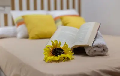 a book with a sunflower laying on top of a bed at Paseo Maritimo 3 Dormitorios in Cádiz