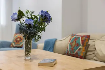 a vase of blue flowers on a table with a book at Paseo Maritimo 3 Dormitorios in Cádiz