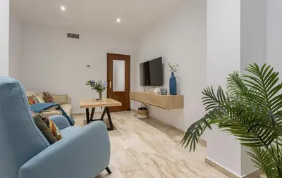 a living room with a blue chair and a tv at Paseo Maritimo 3 Dormitorios in Cádiz