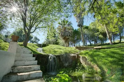a waterfall in a park with stairs next to a creek at El Molino del Pilón by Vintage Travel in Arcos de la Frontera