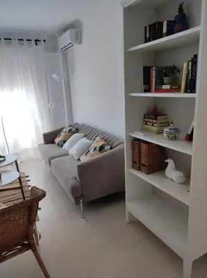 a living room with a couch and a book shelf at Piso a estrenar en el pintoresco Barrio Alto in Sanlúcar de Barrameda