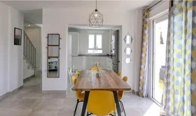 a dining room with a wooden table and yellow chairs at Casa Rosado Beautiful House and 60 m of Private Garden in Conil de la Frontera