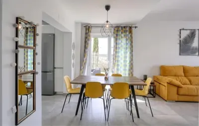 a dining room and living room with a table and chairs at Casa Rosado Beautiful House and 60 m of Private Garden in Conil de la Frontera
