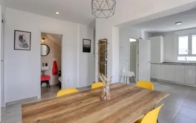 a dining room with a wooden table and yellow chairs at Casa Rosado Beautiful House and 60 m of Private Garden in Conil de la Frontera