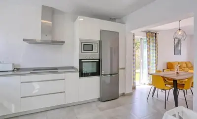 a kitchen with white cabinets and a table with yellow chairs at Casa Rosado Beautiful House and 60 m of Private Garden in Conil de la Frontera