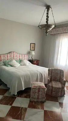 a bedroom with a bed and a chair and a chandelier at Apartamento centrico, 5 bedrooms, 5 baños en-suite in Jerez de la Frontera