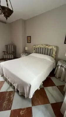 a bedroom with a large white bed with two chairs at Apartamento centrico, 5 bedrooms, 5 baños en-suite in Jerez de la Frontera