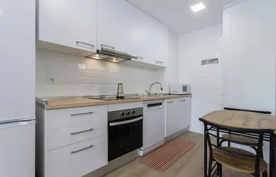 a kitchen with white cabinets and a sink and a table at Holiday Homes - Los Ángeles de Costa Ballena in Chipiona