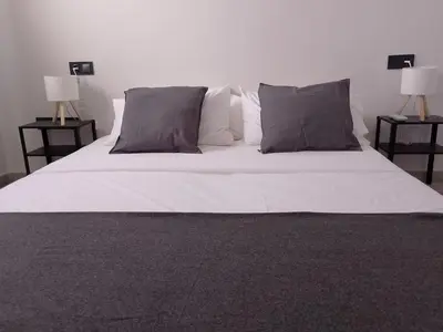 a bed with white sheets and pillows and two lamps at Light and spacious apartment in the heart of San Fernando, Cádiz in San Fernando