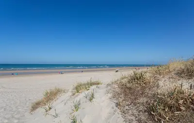 a sandy beach with people in the ocean at Holiday Homes - Ocean Costa Ballena in Cádiz