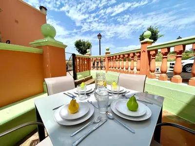 a table with plates and utensils on a balcony at GATU Coqueto in El Puerto de Santa María