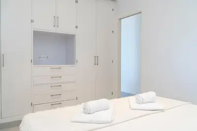 a white bedroom with a bed with two towels at Apartoyou - Balandro Suite in El Puerto de Santa María