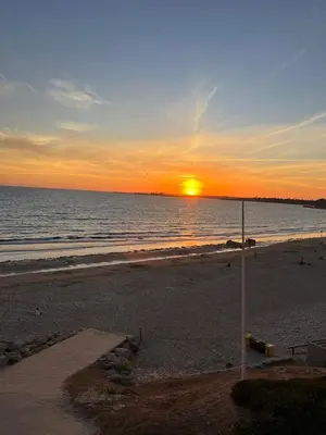 a sunset on a beach with the sun setting at Apartoyou - Balandro Suite in El Puerto de Santa María