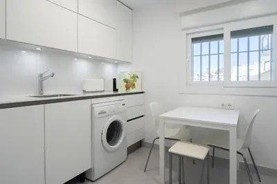 a white kitchen with a washing machine and a table at Apartoyou - Balandro Suite in El Puerto de Santa María