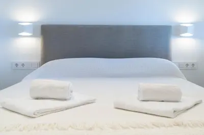 a white bed with two towels on top of it at Apartoyou - Balandro Suite in El Puerto de Santa María