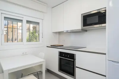 a white kitchen with a laptop on a counter at Apartoyou - Balandro Suite in El Puerto de Santa María