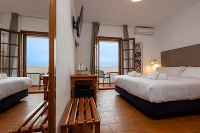 a hotel room with two beds and a balcony at Hotel Tugasa Villa de Algar in Algar