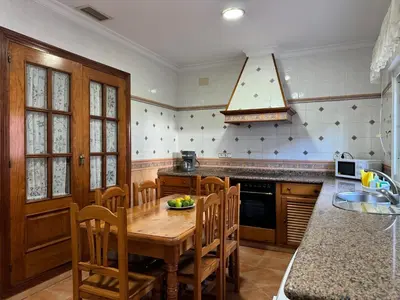 a kitchen with a wooden table and wooden chairs at Chalet San Francisco in Sanlúcar de Barrameda