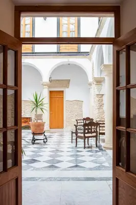 an open door to a courtyard with a table and chairs at Hotel Tugasa Casa Palacio Medina Sidonia in Medina Sidonia