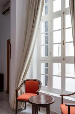 a room with a red chair and a table in front of a window at Hotel Tugasa Casa Palacio Medina Sidonia in Medina Sidonia