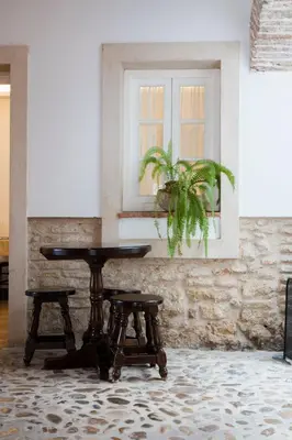 a table and two stools in a room with a window at Hotel Tugasa Casa Palacio Medina Sidonia in Medina Sidonia