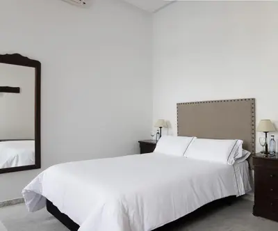 a bedroom with a white bed and a mirror at Hotel Tugasa Casa Palacio Medina Sidonia in Medina Sidonia