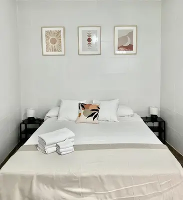 a white bedroom with a bed with towels on it at Apartamento en El Puerto de Santa María in El Puerto de Santa María
