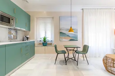 a kitchen with blue cabinets and a table and chairs at La Casa de la Plaza del Arroyo - Traditional Luxury in Jerez in Jerez de la Frontera