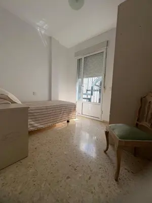 a bedroom with a bed and a chair and a window at Brisas de Las Piletas in Sanlúcar de Barrameda