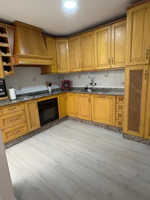 a kitchen with wooden cabinets and a tile floor at Brisas de Las Piletas in Sanlúcar de Barrameda