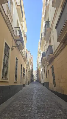 an empty street in an alley between buildings at El Tesoro de Cadiz in Cádiz