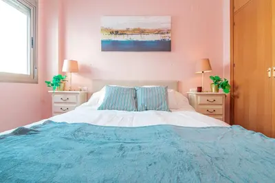a bedroom with a large bed with a blue blanket at Edomus Playa de la Costilla in Rota