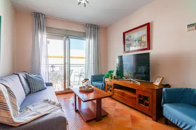 a living room with a flat screen tv and blue chairs at Edomus Playa de la Costilla in Rota